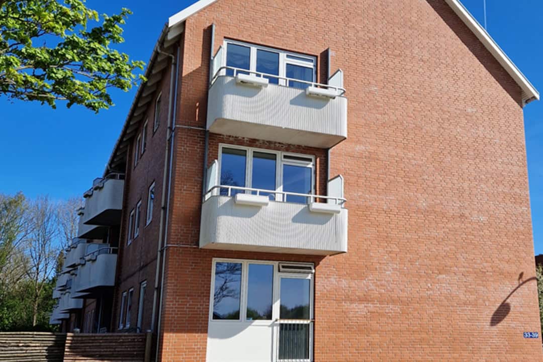 Facaderenovering af murstenshus med hvide altaner i Rødovre